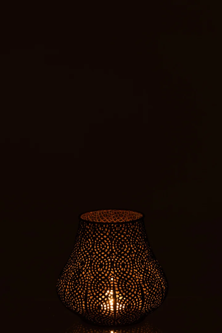 De Theelichthouder Oosters Metaal Goud Antiek Groot gloeit met een brandende kaars, het ingewikkelde stippelpatroon werpt een warm, zacht licht tegen een donkere achtergrond.