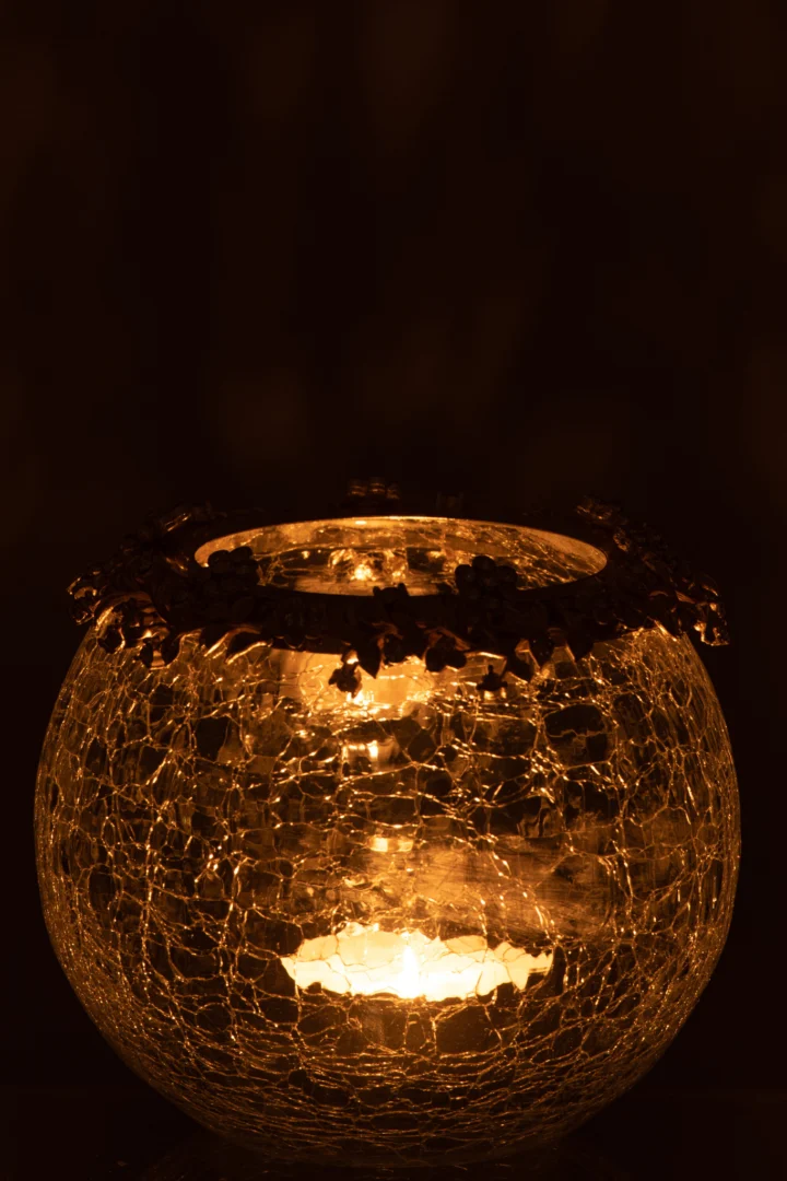 Theelichthouder Volve Metaal Glas Goud Transparant Groot heeft een rond, gebarsten glazen ontwerp dat warm oplicht in het donker, zacht gouden licht werpt en het elegante, reflecterende oppervlak benadrukt.