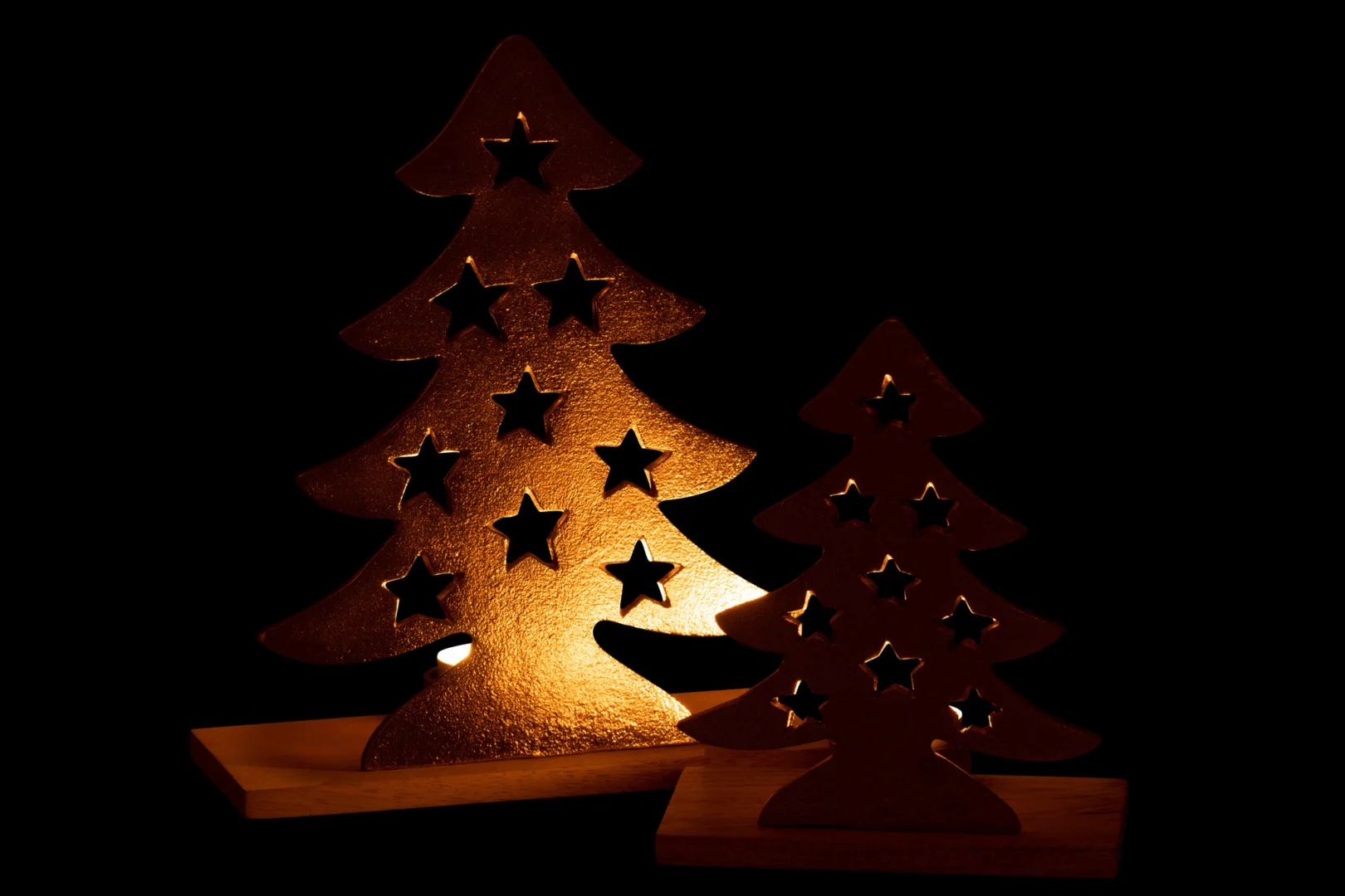 De Theelichthouder Kerstboom Aluminium/Hout Natuur/Goud Groot is een decoratief kerstboomsilhouet met stervormige uitsparingen, staand op een houten voet en prachtig verlicht tegen een donkere achtergrond.