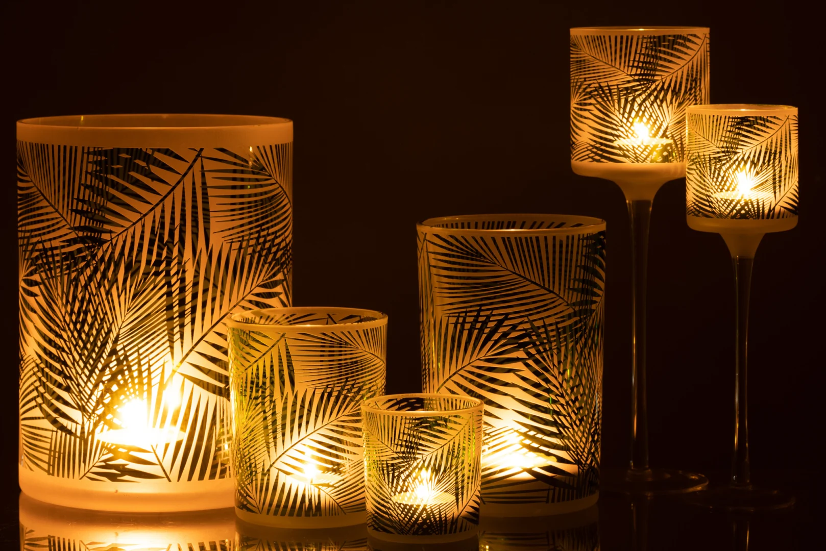 De Kaarsenhouder Orkaan Tropisch Glas Groen Groot schittert warm tegen een donkere achtergrond. Het elegante groene tropische glas en de lange steel geven elke omgeving een gezellige sfeer.