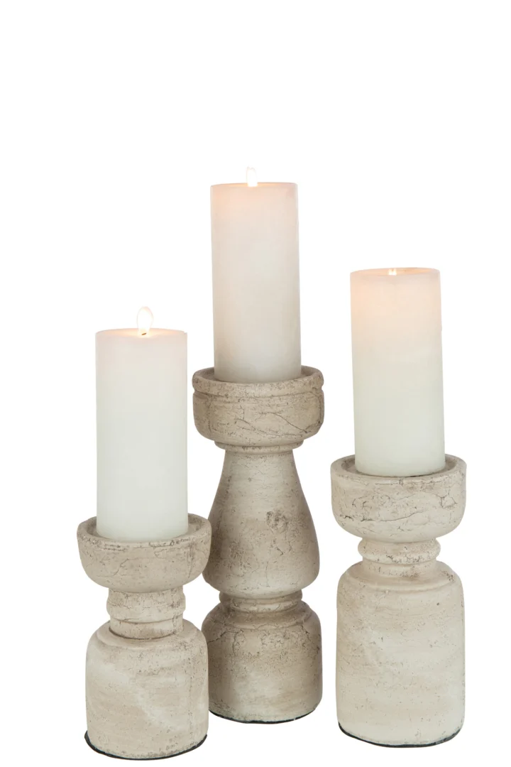 Een trio witte kaarsen, elk gloeiend op een Kaarsenhouder Terracotta Beige Groot van verschillende vormen en hoogtes, staan tegen een eenvoudige witte achtergrond.