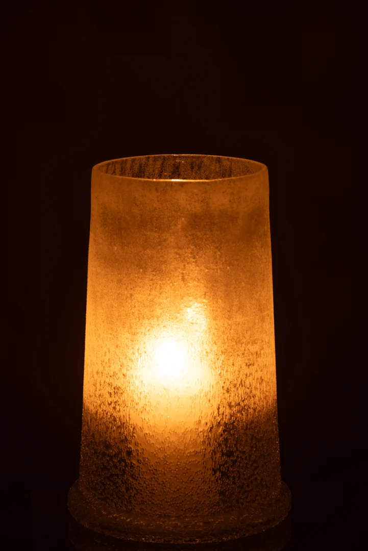 De Kaarsenhouder Orkaan Suikerglas Wit Groot straalt warm vanuit de matglazen houder met textuur tegen een donkere achtergrond.