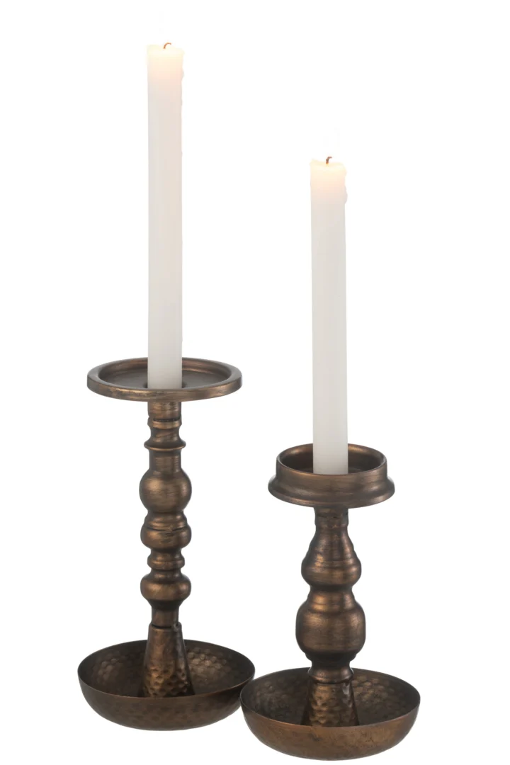 Twee brandende witte kaarsen zitten in bijpassende Kaarsenhouder Jere Metaal Bruin kandelaars met brede, ronde voet, een gehamerde textuur en een klassiek bronzen ontwerp in antieke stijl.