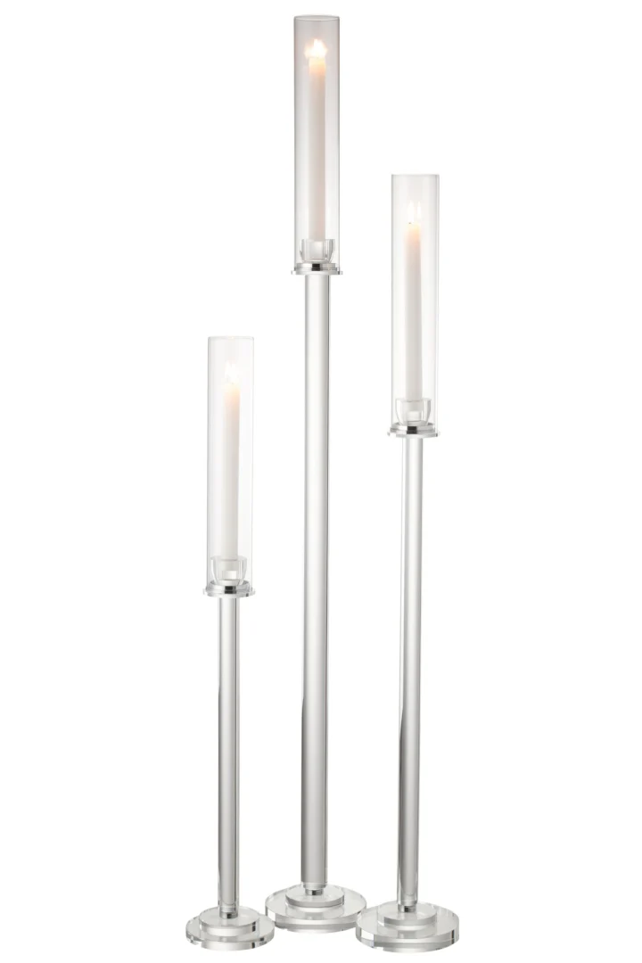 De Kaarsenhouder Moira Glas Transparant Groot bestaat uit drie hoge, cilindervormige glazen kandelaars met zilveren voet en doorzichtige kap, die elk een brandende witte kaars tonen op verschillende hoogtes tegen een effen witte achtergrond.