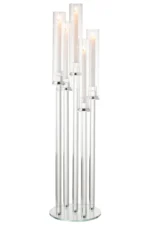 De Kaarsenhouder 5 Dun Glas Transparant heeft hoge, heldere glazen houders van verschillende hoogtes, elk met een gloeiende witte taps toelopende kaars, elegant samen gepresenteerd op een ronde glazen voet.