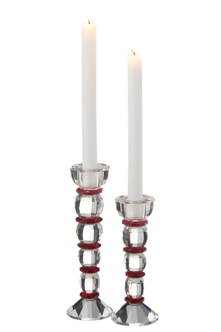 Twee brandende witte kaarsen staan in Kaarsenhouder Annie Kristalglas Rood/Transparant Groot kandelaars van verschillende hoogtes, elk helder kristal met opvallende rode accenten.