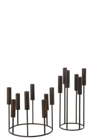 De Kaarsenhouder Pierre IJzer Zwart Set van 2 heeft twee moderne zwart metalen kandelaars: een ronde en lage, de andere hoog en ovaal, beide met cilindrische sleuven op verschillende hoogtes en een open, minimalistisch ontwerp.