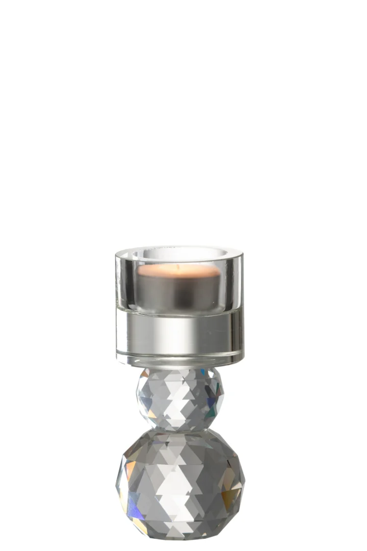 Een kleine brandende kaars gloeit in de Kaarsenhouder Kristalglas Transparant, een heldere facethouder met geometrische vormen die het licht weerkaatsen en prismatische effecten creëren tegen een effen witte achtergrond.