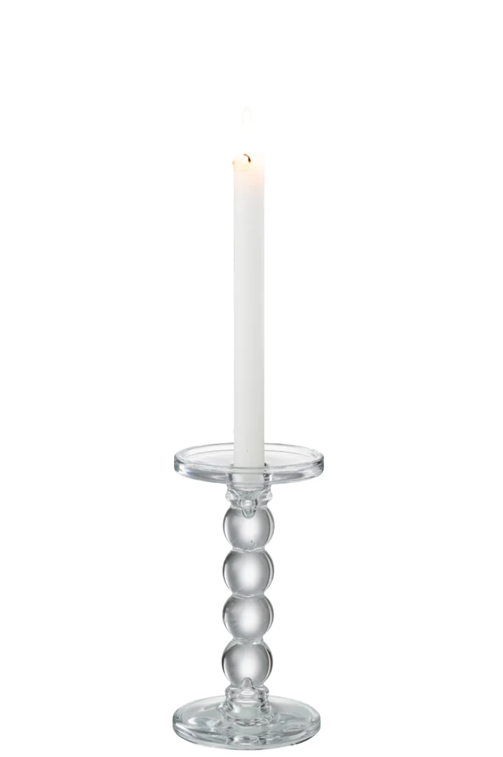 Een brandende witte conische kaars staat rechtop in de Kaarsenhouder Druppels Glas Transparant Medium, een heldere glazen houder met een rond, gestapeld ontwerp, tegen een effen witte achtergrond.