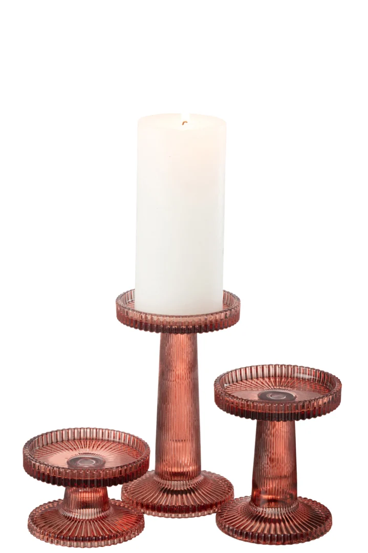 De Kaarsenhouder Nelly Glas Oranje Set 3 bestaat uit drie geribbelde glazen kandelaars in verschillende hoogtes met een ronde, gestructureerde basis en bovenkant. In de ene houder past een brandende hoge witte pilaarkaars, terwijl de andere twee leeg zijn.