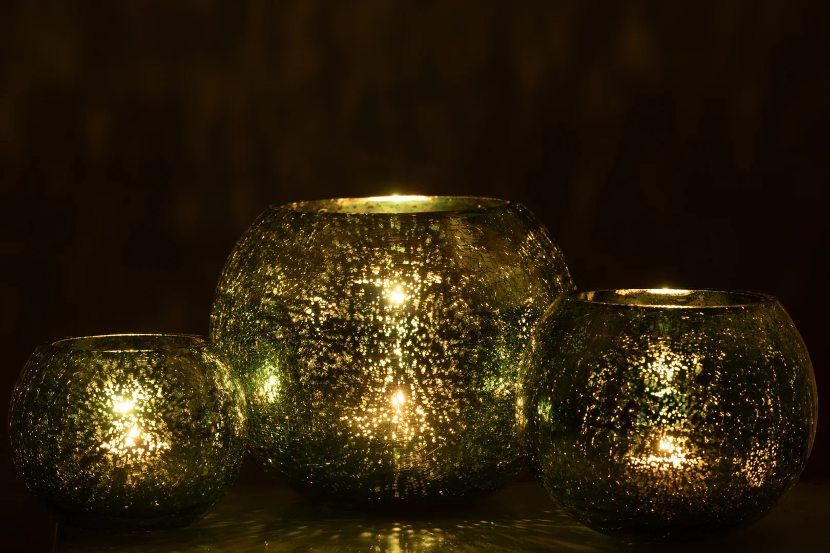 Theelichthouder Bal Craquelure Glas Watergroen Groot is een grote, ronde, groene glazen kandelaar met een gespikkeld oppervlak dat warm oplicht in het donker en zachte reflecties geeft voor een gezellige sfeer.