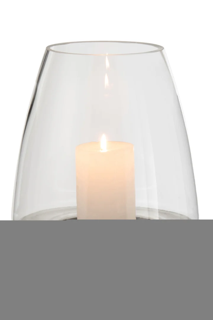 De Kaarsenhouder Orkaan Aardewerk Glas Zilver houdt een brandende witte pilaarkaars vast in het heldere, ronde glas, met een zachte vlam in het midden. De achtergrond is effen en overwegend wit.