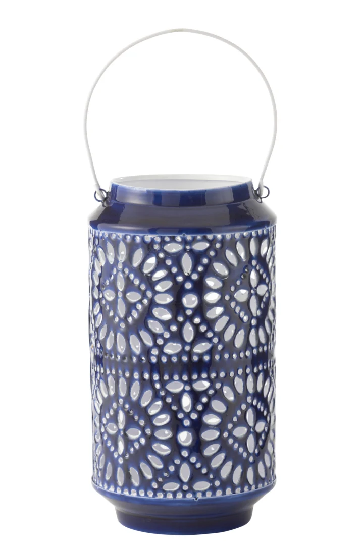 De Kaarsenhouder Orkaan Nag IJzer Blauw Wit Groot is een cilindervormige lantaarn van blauw keramiek met een wit metalen handvat en ingewikkelde bloemvormige uitsparingen die licht doorlaten.