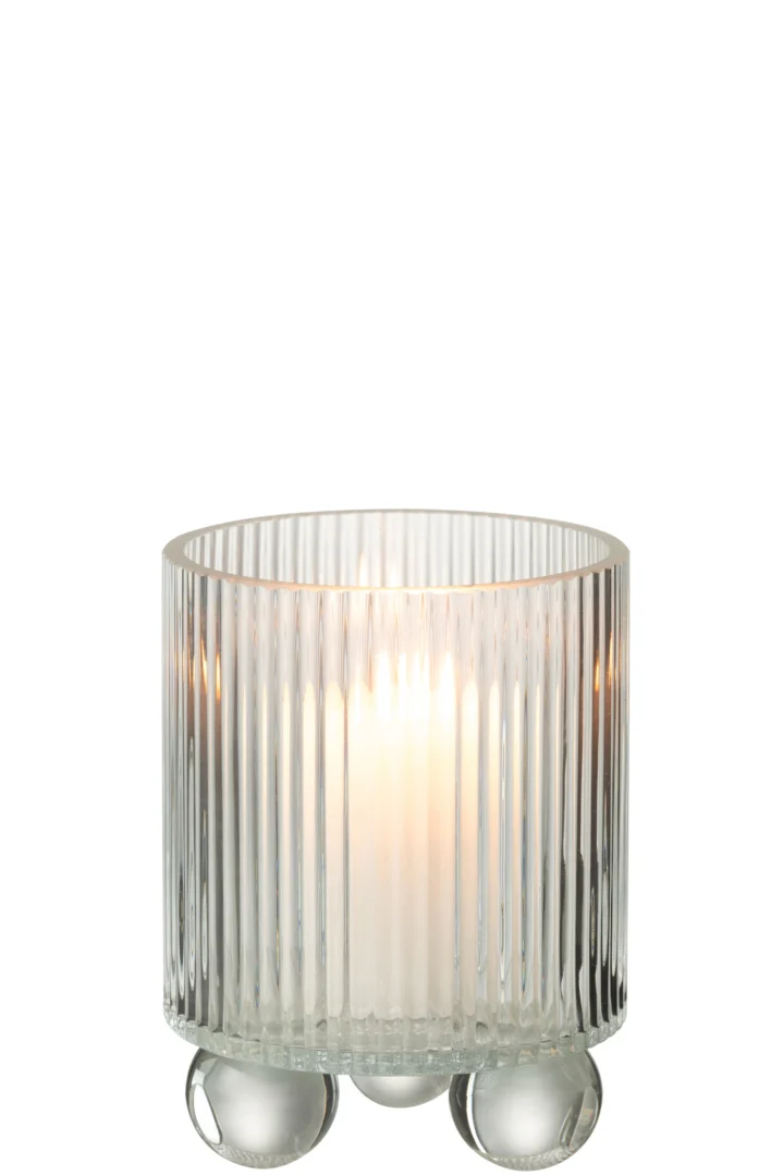 De Kaarsenhouder Orkaan Clara Glas Klein is een brandende kaars in een heldere, geribbelde glazen houder met verticale lijnen en ronde pootjes, die zacht gloeit tegen een witte achtergrond.