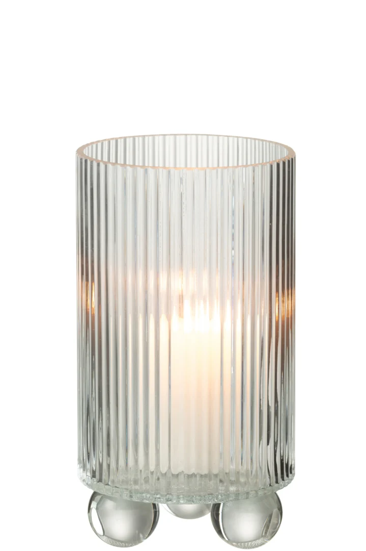 De Orkaan Clara Glas Transparant Groot kaarsenhouder heeft een brandende kaars in een heldere, verticaal geribbelde glazen houder met drie ronde glazen voetjes, die warm oplicht.