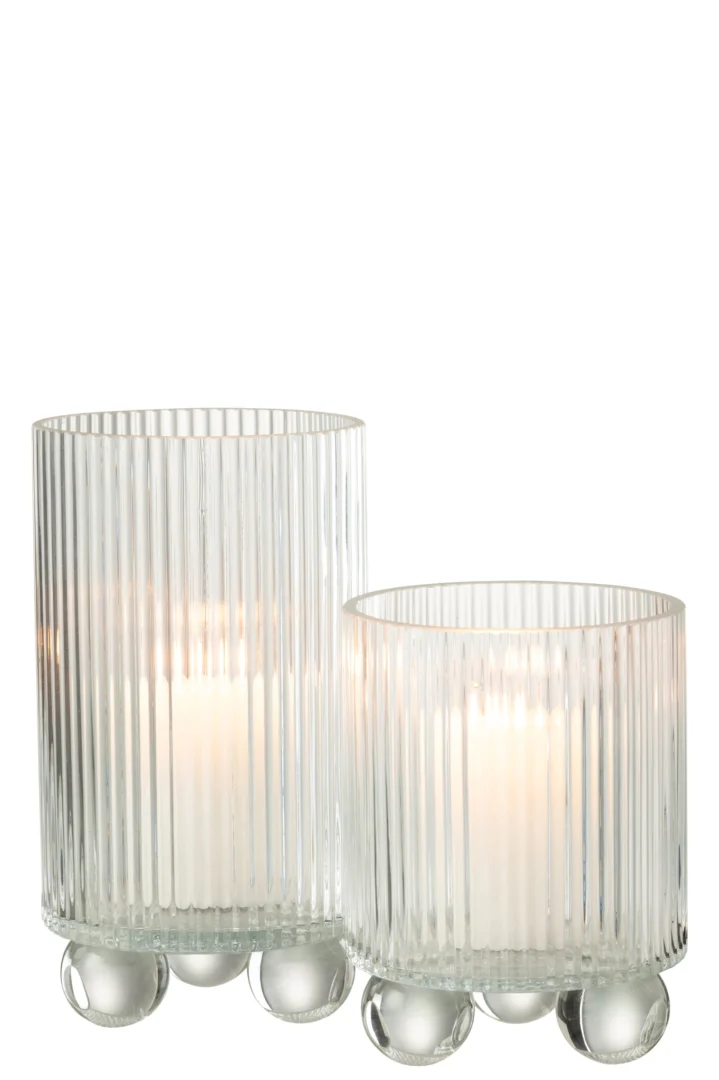 De Orkaan Clara Glas Transparant Groot kaarsenhouder heeft geribbeld glas met verticale groeven, ronde glazen bolpootjes en wordt geleverd in twee maten, elk met een brandende witte kaars erin. De ene houder is hoger dan de andere.