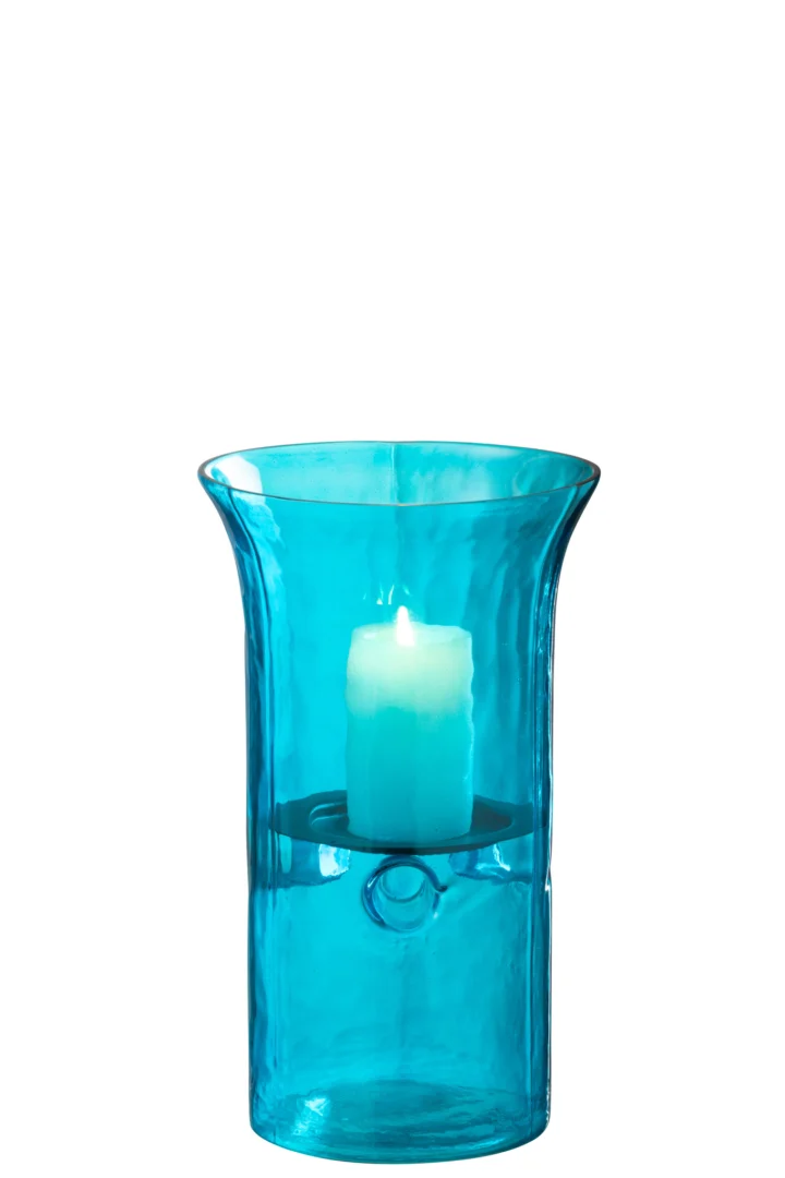 De Orkaan Tarifa Smal Glas Azuurblauw Klein - Kaarsenhouder is een blauwe glazen stormkandelaar met een uitlopende rand en een brandende blauwe pilaarkaars op een cirkelvormig plateau, tegen een witte achtergrond.