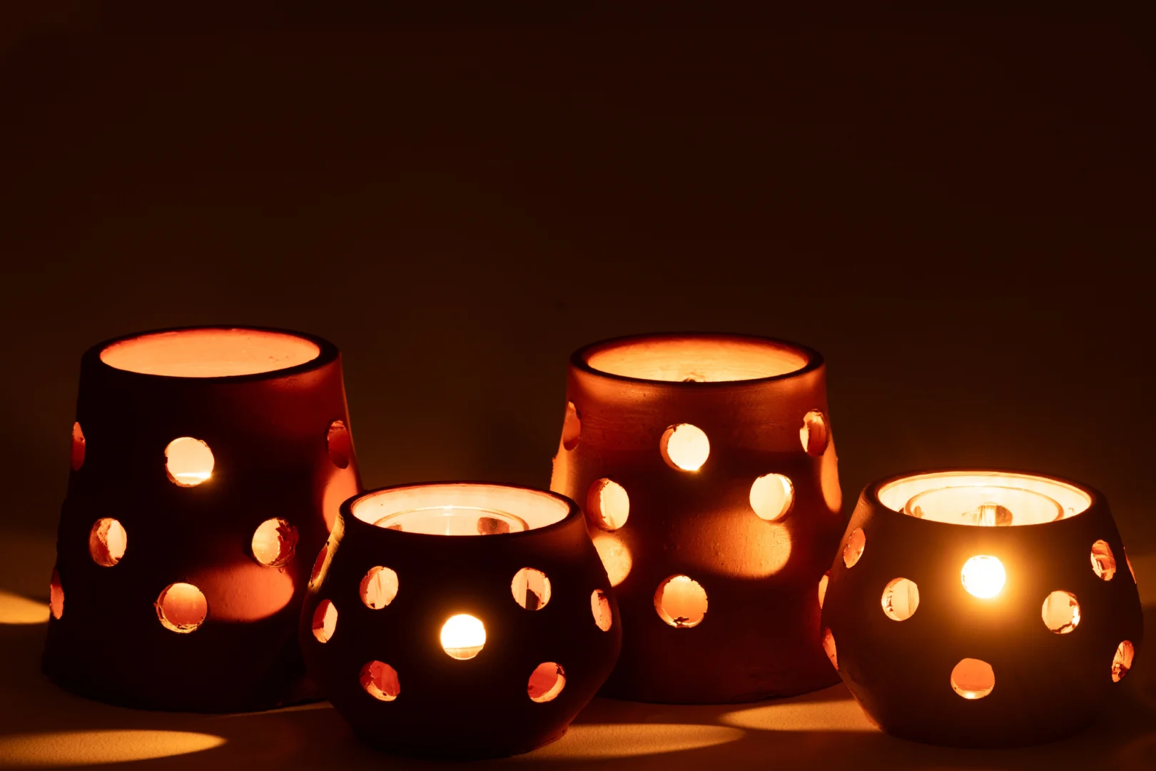 De Theelichthouder Gaia Smal Klei Glas Rood Bruin Set van 2 werpt een zachte, warme gloed door het ontwerp van klei en glas en creëert zachte lichtpatronen op de omringende oppervlakken.