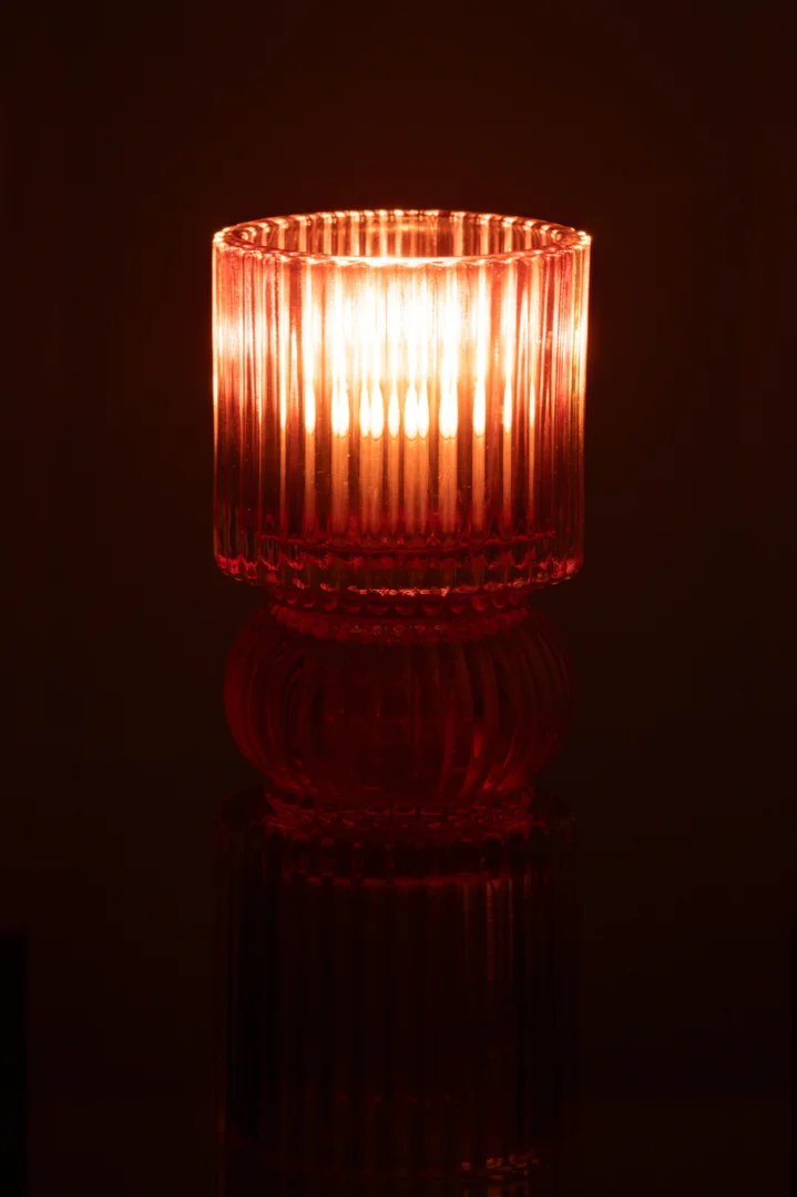 De Kaarsenhouder Jazzy Glas Mix heeft een kaars in een geribbelde rode glazen houder die warm gloeit in het donker en een zacht, sfeervol licht geeft.