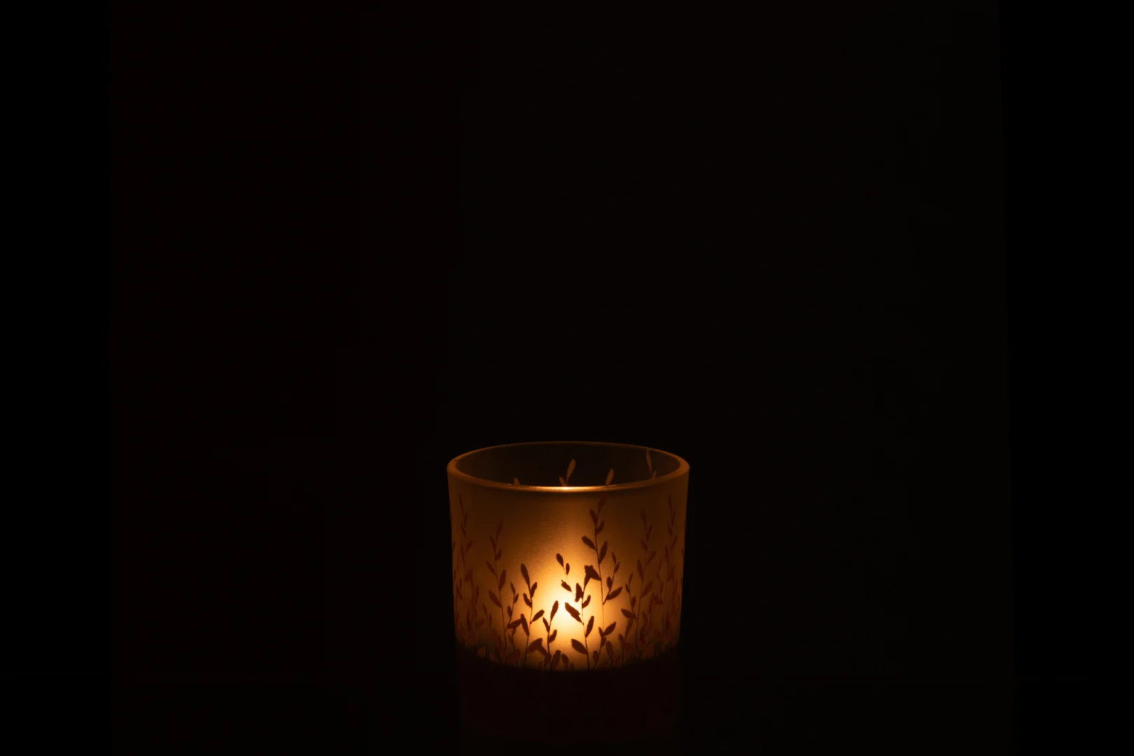 De Sally Glas Oranje Extra Klein - Theelichthouder Kaarsenhouder werpt een warme, zachte gloed uit de glazen houder met bladmotief en verlicht de duisternis met zacht kaarslicht.