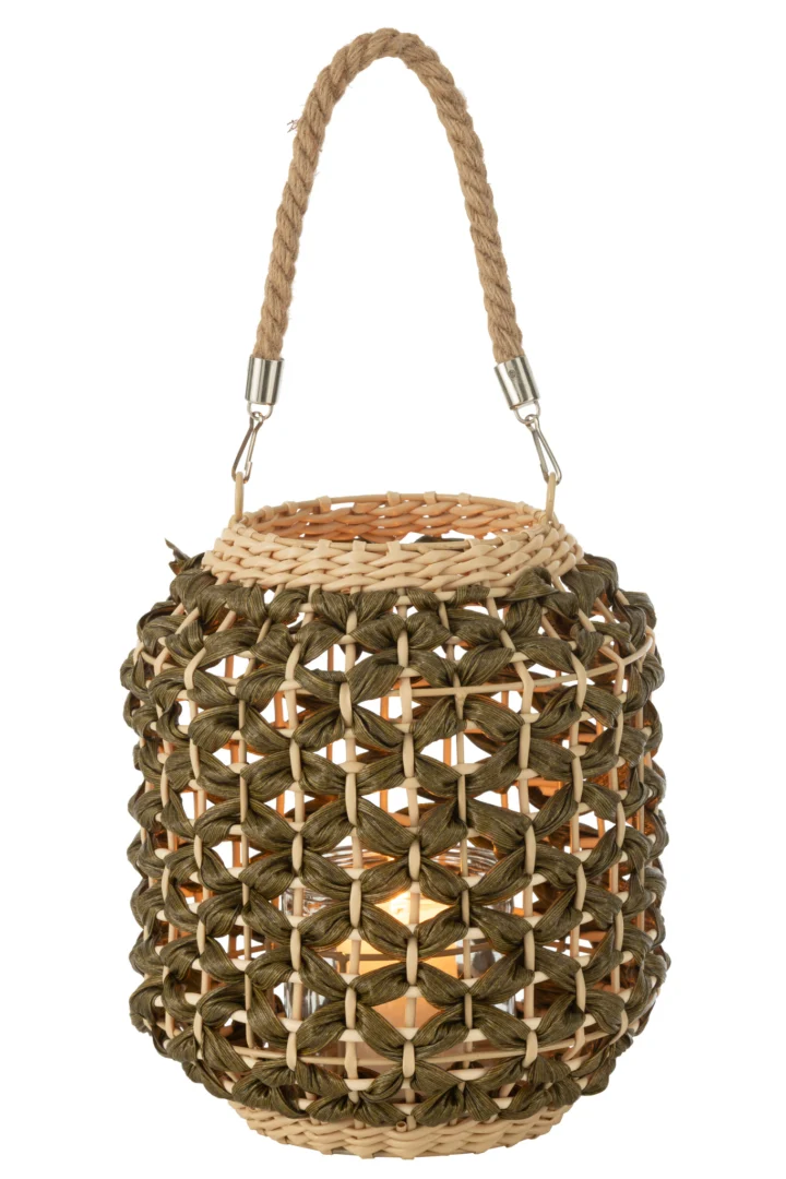 De Lantaarn Ubeda Riet Groen Natuurlijk is een cilindervormige geweven lantaarn gemaakt van natuurlijke en groene vezels, met een handvat van touw en een kaars binnenin voor een gezellige, warme gloed.