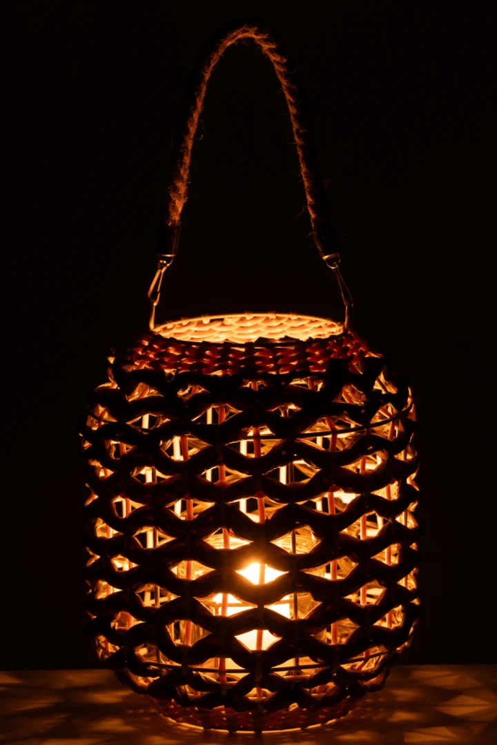 De Lantaarn Ubeda Riet Groen Natuurlijk is een gloeiende lantaarn met een rieten ontwerp en een handvat van touw, die warm licht geeft in het donker.