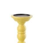 De Kaarsenhouder Dumbbel Mangohout Geel is een kandelaar van geel mangohout met een ronde zwarte bovenkant, voorzien van een gebogen decoratieve steel en een brede, stabiele voet.