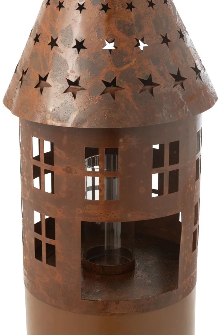De Kaarsenhouder Ster IJzer Roestbruin is een rustieke, metalen lantaarn in de vorm van een klein huisje met ster- en raamuitsparingen en een verweerde bruine afwerking, met binnenin een glazen cilinder voor een kaars of een lampje.