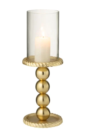 De Kaarsenhouder Aluminium Goudkleurig Groot heeft een brandende witte pilaarkaars in een houder van helder glas, ondersteund door een gouden standaard met drie gestapelde bollen en goudkleurige textuuraccenten op de basis en de rand.