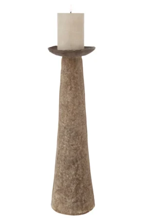 Een witte pilaarkaars brandt op de Kaarsenhouder Aluminium Bruin Groot, een hoge, rustieke bruine aluminium kandelaar met een brede voet en smalle bovenkant.