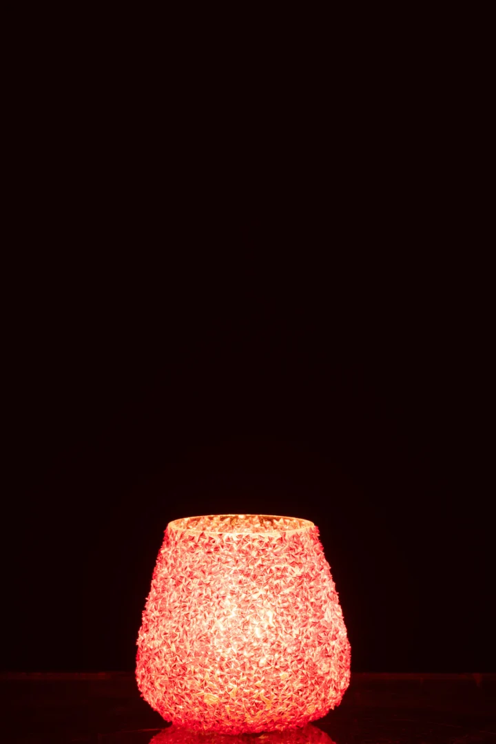 De Theelichthouder Glas Kralen Donker Oranje Klein staat in het midden onderaan op een donkerzwarte achtergrond. De diep oranje glazen kralen stralen warm en accentueren het gedetailleerde oppervlak.