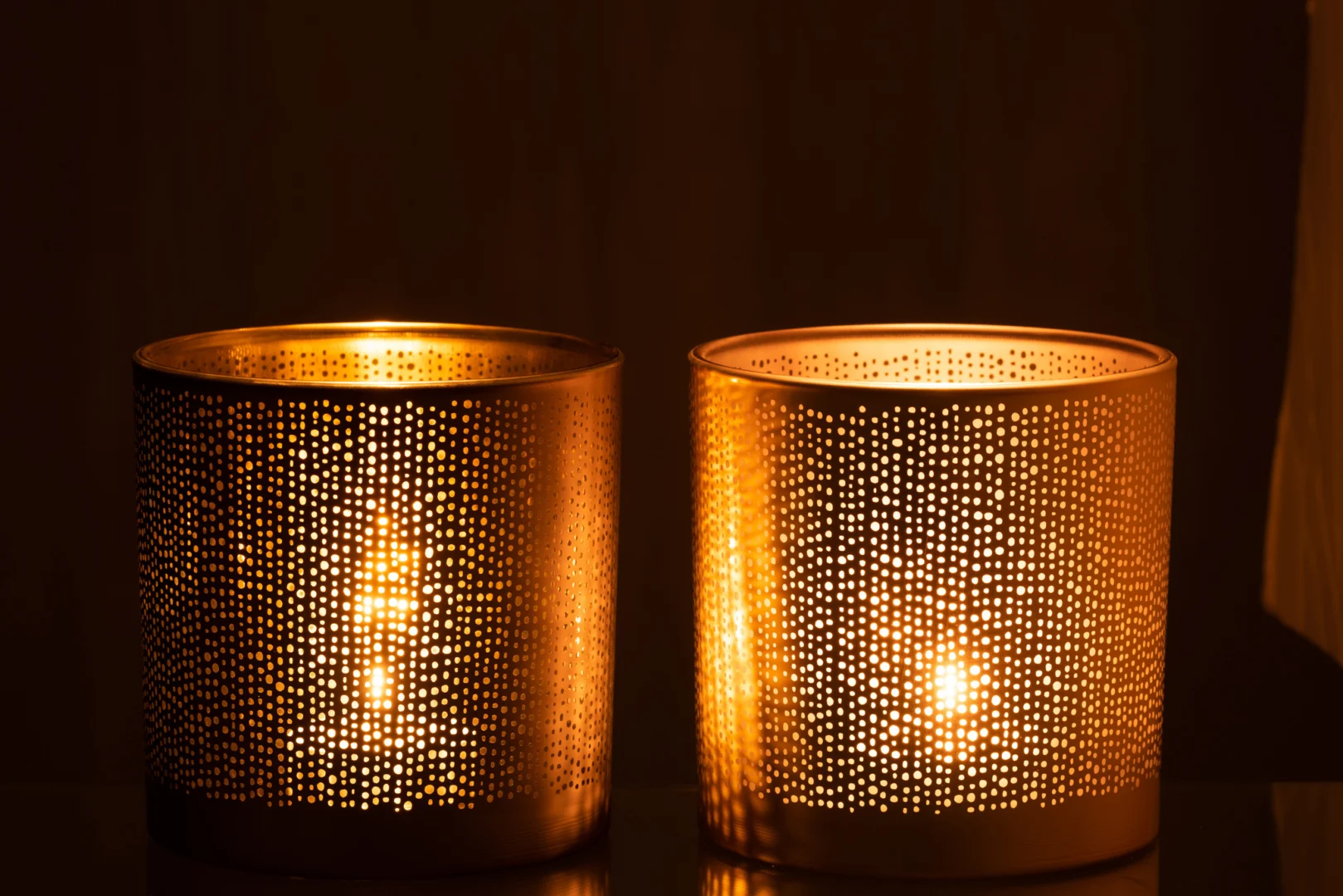 De Theelichthouder Glas Zilver Goud Gespikkeld Groot Set 2 heeft twee grote glazen kandelaars met een gevlekte zilvergouden afwerking, die een warme, patroonachtige gloed in het donker werpen en de oppervlakken eromheen verlichten.