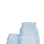 Twee transparante lichtblauwe Orkaan Gestreept Glas kaarsenhouders hebben verticale ribbelpatronen. De kleinere houder is rond en kort; de grotere is langer en iets breder, beide leeg op een witte achtergrond.
