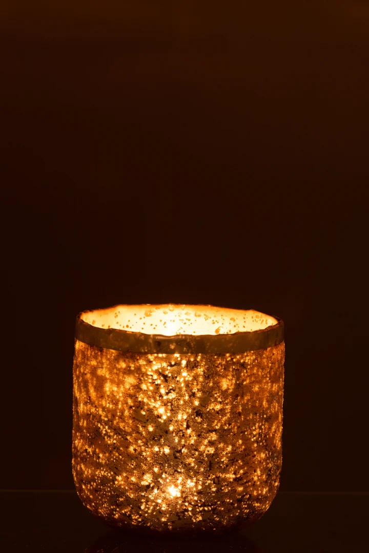 De Theelichthouder Frosty Glas Oudroze Groot heeft een houder van gestructureerd glas in een oudroze tint, die een warme, zachte gloed werpt tegen een donkere achtergrond voor een gezellige, uitnodigende sfeer.