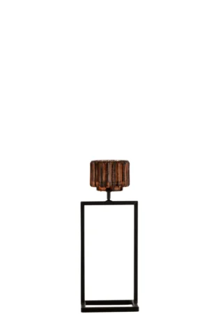 De Theelichthouder Rechts Glas Bruin Klein heeft een kleine bruine glazen kandelaar met een geribbelde textuur op een hoge, rechthoekige zwarte metalen standaard met open frame, tegen een effen witte achtergrond.