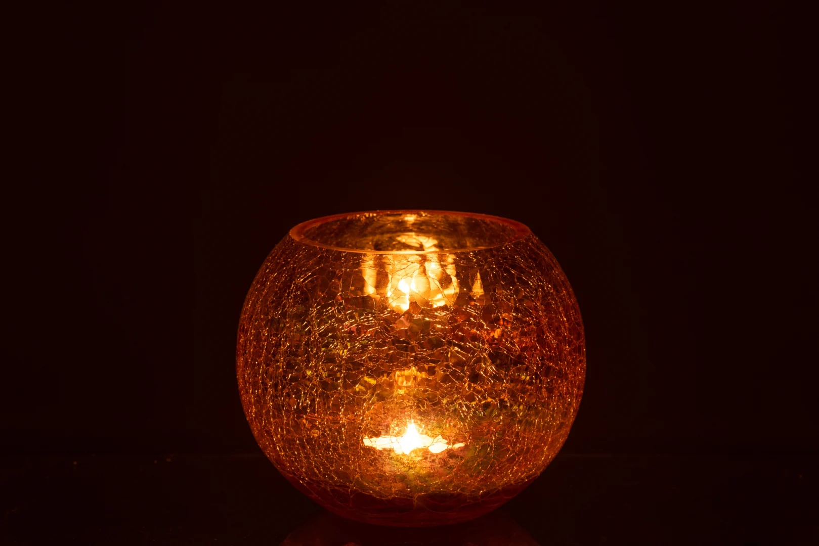 De Kaarsenhouder Orkaan Lichtbal Craquelure Glas Amber Groot werpt een warme gloed door de ronde, gestructureerde amberkleurige glazen houder en verlicht de duisternis met gezellig licht.