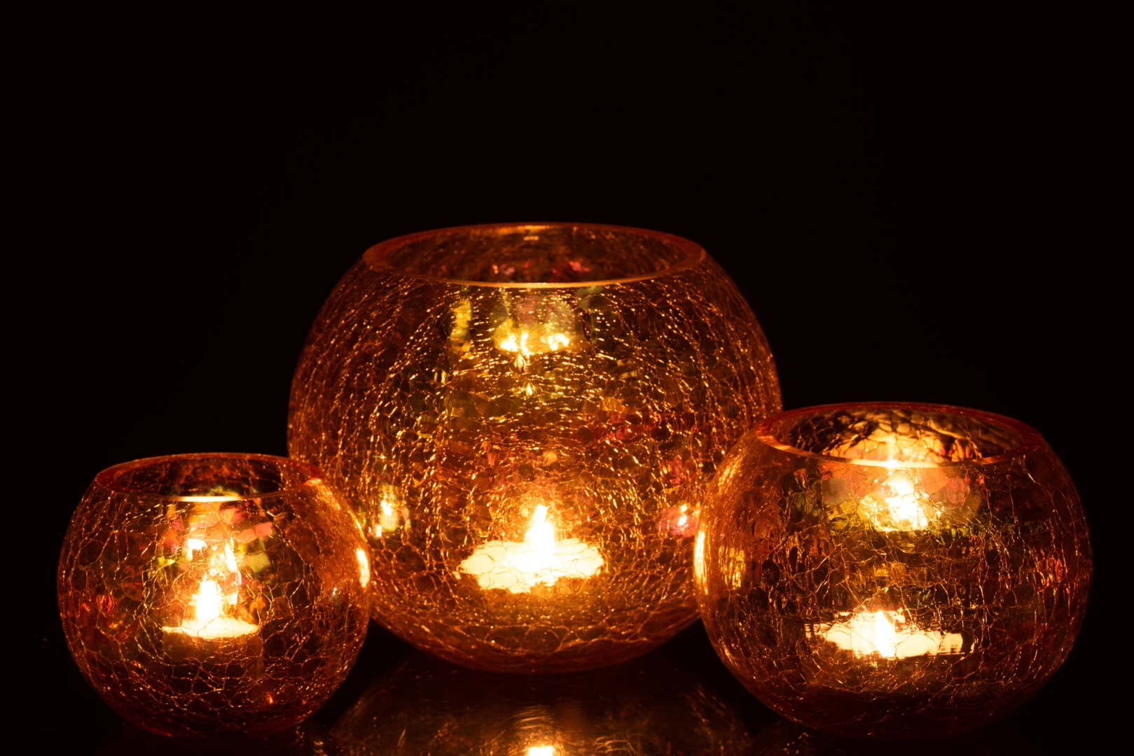 De Kaarsenhouder Orkaan Lichtbal Craquelure Glas Amber Groot is een grote, ronde glazen kandelaar met een gebarsten amberkleurige afwerking die warm gloeit wanneer hij aangestoken wordt en een gezellige en uitnodigende sfeer creëert.