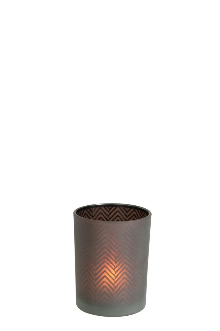 De Kaarsenhouder Orkaan Chevron Glas Bruin Klein is een brandende kaars in een decoratieve, matbruine glazen houder met een subtiel chevronpatroon, die warm oplicht tegen een effen witte achtergrond.