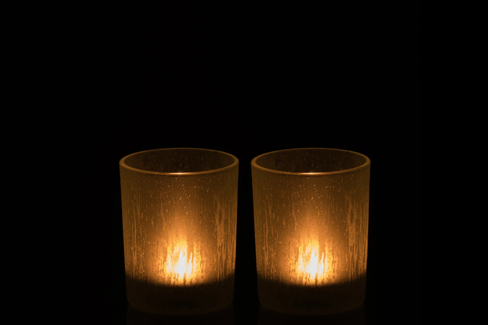 Twee aangestoken Theelichthouder Glas IJsblauw Groen Groot Set 2 kaarsen gloeien zacht in matte houders tegen een donkere achtergrond.