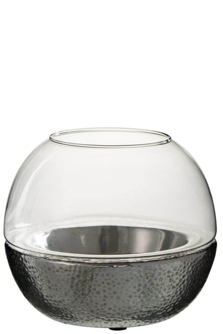 De Kaarsenhouder Orkaan Bal Aardewerk Glas Zilver Groot is een grote ronde glazen kandelaar met een brede opening, gladde heldere bovenkant en een gehamerd zilveren keramieken voet.