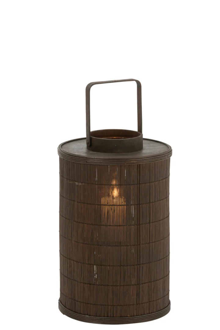 De Kaarsenhouder Lantaarn Cilinder Bamboe Bruin Groot is een grote, donkerbruine cilindrische bamboelantaarn met een plat metalen handvat. Een kaars binnenin werpt een warme, zachte gloed door de geweven bamboe buitenkant.