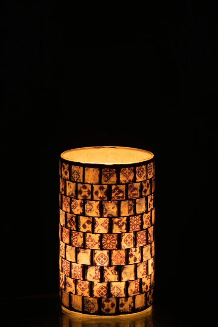 Een brandende kaars gloeit warm in de Theelichthouder Mozaïek Glas Jeansblauw Groot, een decoratieve kandelaar met een prachtig jeansblauw mozaïekpatroon, dat prachtig afsteekt tegen een donkere achtergrond.