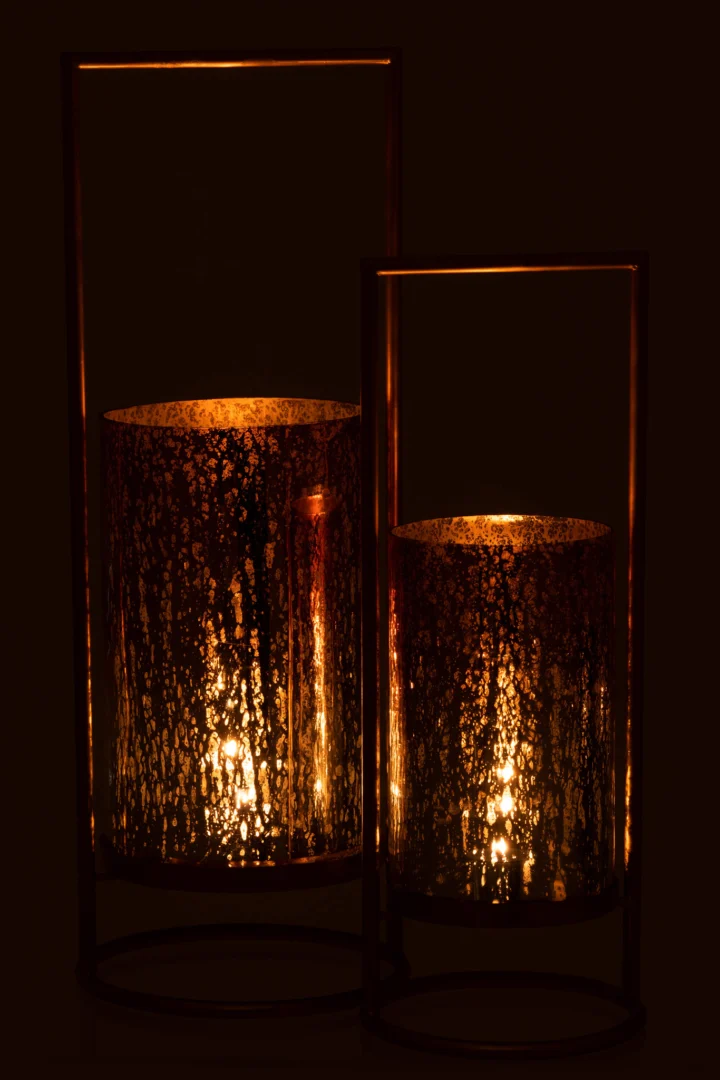 De Kaarsenhouder Orkaan Virginie Glas Metaal Goud Roze Groot heeft twee brandende kaarsen in houders van gestructureerd glas met gouden metalen frames, die warm oplichten in het donker en zachte, flikkerende schaduwen werpen.