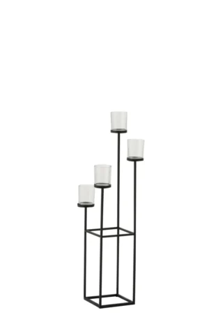 De Kaarsenhouder Metaal Glas Zwart 4 Delig is een moderne zwart metalen kandelaar met vier glazen votiefhouders op verschillende hoogtes op slanke staven, allemaal geplaatst op een rechthoekig open frame.
