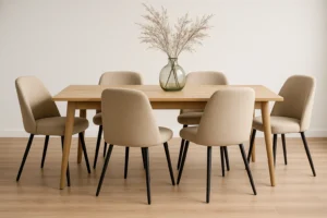 Een minimalistische eetkamer heeft een houten tafel omringd door zes beige gestoffeerde stoelen - dit zijn de voordelen van comfortabel zitten. Op de tafel rust een glazen vaas met gedroogde grassen op een lichte houten vloer tegen een effen witte muur.