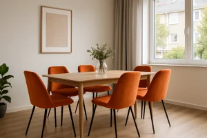 Een moderne eetkamer met een lichte houten tafel omringd door zes oranje fluwelen stoelen -hoe kies je de juiste oranje eetkamerstoelen- plus een vaas met groen, een groot raam met beige gordijnen, abstracte kunst en een potplant in de hoek.