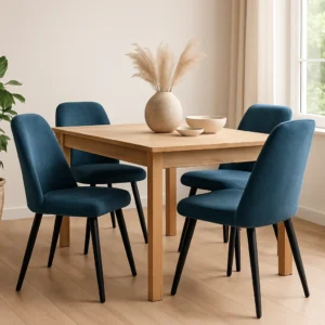 Een houten eettafel met daaromheen vier stoffen blauwe eetkamerstoelen. Op de tafel staan een beige vaas met gedroogd pampagras en twee ondiepe schalen. De kamer heeft een lichte houten vloer en een groot raam.