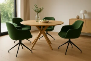 Een moderne eethoek met een ronde houten tafel en vier groene stoelen, perfect voor wie zich afvraagt: waarom zijn groene eetkamerstoelen zo populair? Een glazen vaas, appels en lichte houten vloeren creëren een frisse, uitnodigende ruimte.