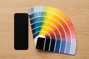 Op een houten oppervlak ligt een waaier met een breed scala aan kleuren, van donkere tot heldere tinten. Een aparte effen zwarte staal is links geplaatst, perfect voor het beantwoorden van de vraag: welk kleurenpalet bevat zwart?.