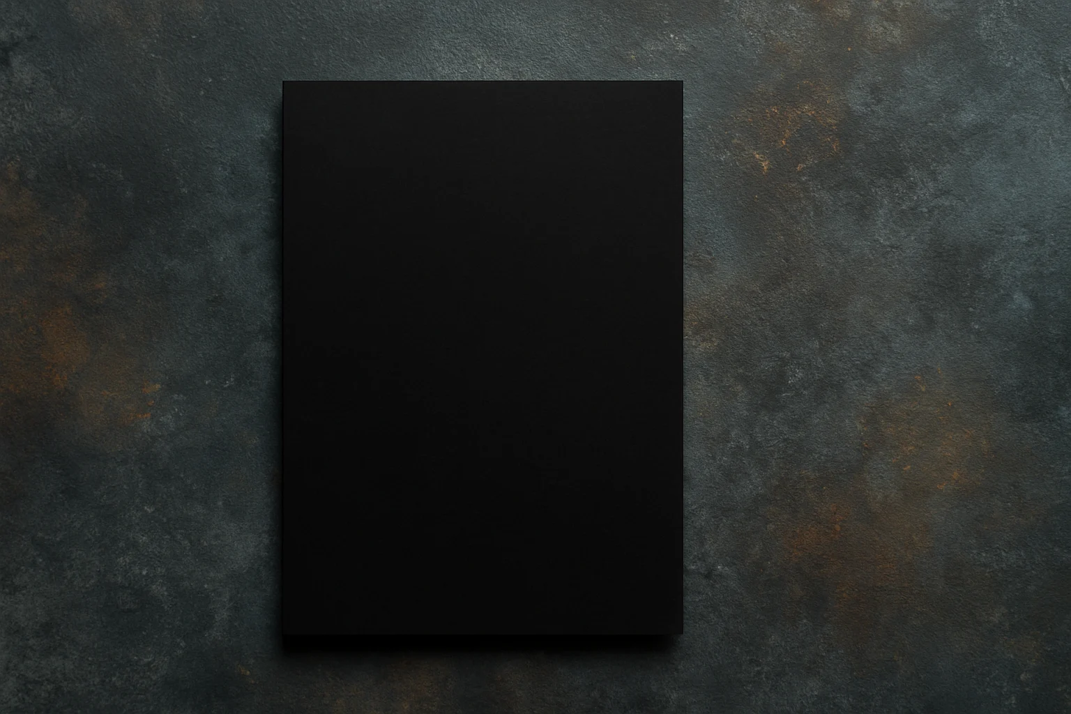 Een effen zwart rechthoekig vel papier, dat duidelijk laat zien welke kleur zwart absorbeert, is gecentreerd op een gestructureerd donkergrijs en bruin oppervlak, van bovenaf gezien. Het ongemarkeerde papier steekt af tegen de gevlekte achtergrond.